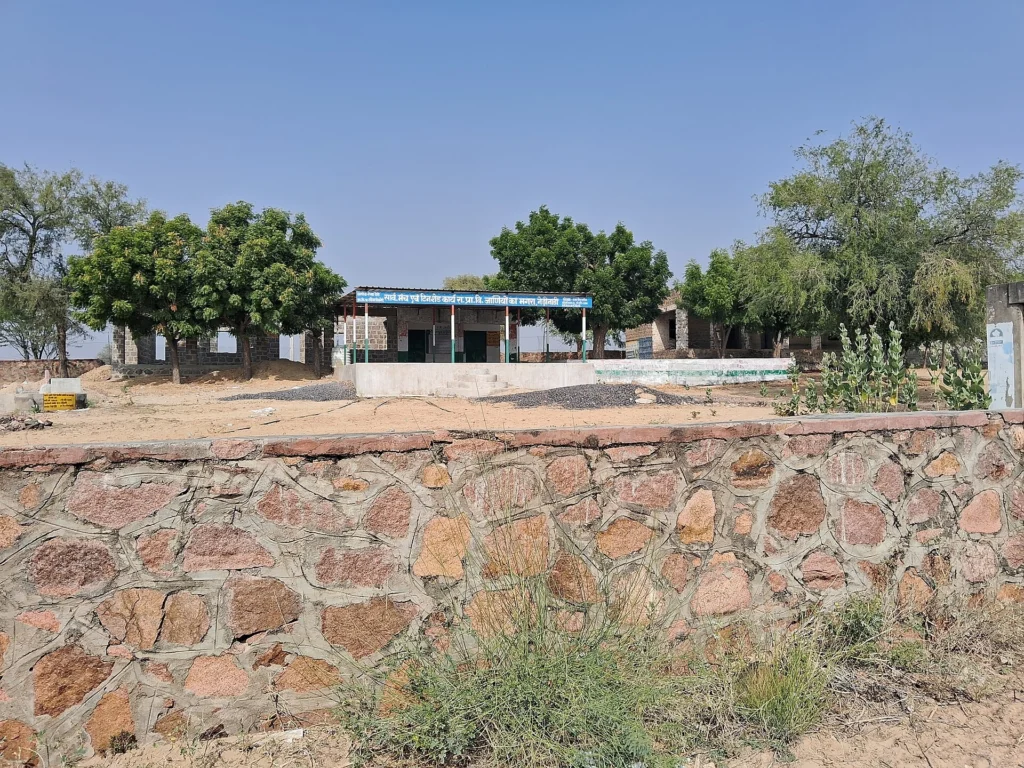 Government primary school buildings behind a stone boundary wall